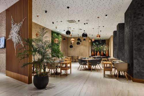 布尔诺Hotel Passage的一间设有桌椅的餐厅,种植了植物