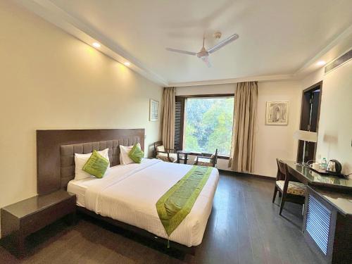 新德里Amber Inn by Orion Hotels的一间卧室配有一张床、一张书桌和一个窗户。