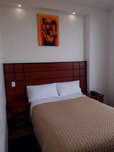 SangolquíHOTEL DEL RIVER MONUMENTO的一间卧室配有一张大床和木制床头板