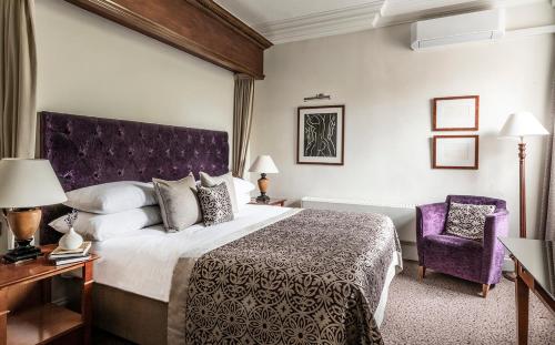 阿施精选布兰德萨奇广场酒店&SPA的酒店客房设有一张大床和一张紫色椅子