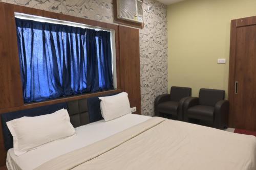 德奥加尔Hotel Bharati的一间卧室配有一张床,窗户配有两把椅子