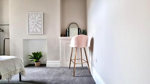 卡迪夫Moorland House by Switchback Stays的带壁炉的客房内的粉红色椅子