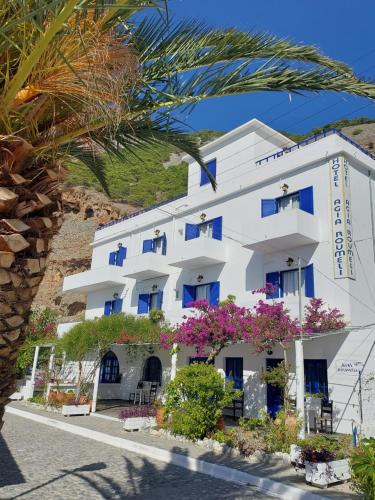 阿吉亚努美利Agia Roumeli Hotel的白色的建筑,有蓝色的窗户和鲜花