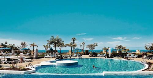 圣乌尔苏拉Residencial La Quinta Park Suites的度假村的游泳池,人们在里面游泳