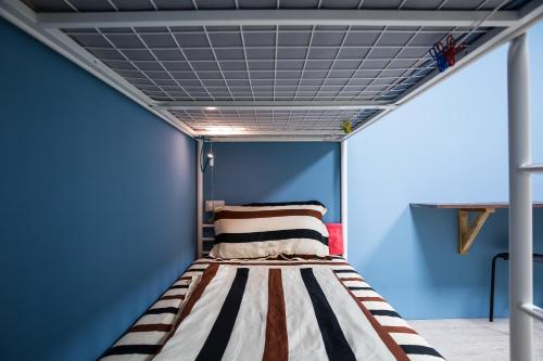 鱼池乡日月彩舟 日月潭背包客旅店 Sun Moon Lake Rainbow SUP Hostel的蓝色客房的一张床位,天花板