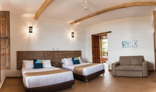 布卡拉曼加Hotel Hacienda La Fe的酒店客房,配有两张床和椅子
