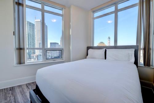 米西索加Grand Royal condos SQ One Mississauga的卧室设有一张白色大床和两个窗户。