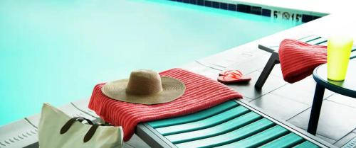 达拉斯Home2 Suites By Hilton Dallas Medical District Lovefield, Tx的坐在泳池旁的毛巾堆上的帽子