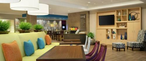 达拉斯Home2 Suites By Hilton Dallas Medical District Lovefield, Tx的一间带桌椅和电视的餐厅