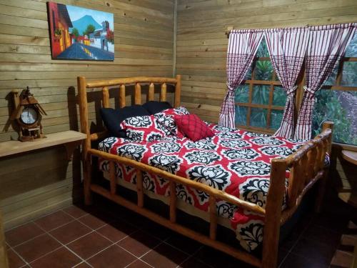 圣地亚哥阿蒂特兰Chalet in the Woods的一间卧室配有一张带红白毯子的木床