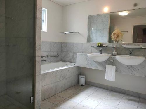South StradbrokeSpacious Waterfront Apartment Couran Cove的浴室设有2个水槽、浴缸和镜子