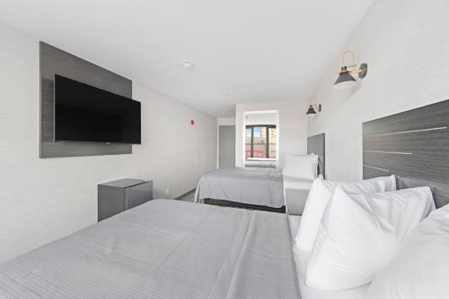 布朗克斯Hotel TREMONT Bronx Yankee Stadium的一间白色卧室,配有两张床和一台平面电视