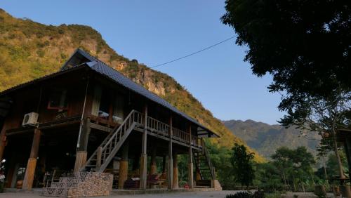 枚州县Nha Tan - Mai Chau Homestay and Tours的一座大建筑,背景是一座山