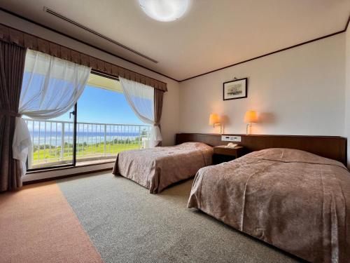 奄美珊瑚棕榈旅馆的一间卧室设有两张床和大窗户