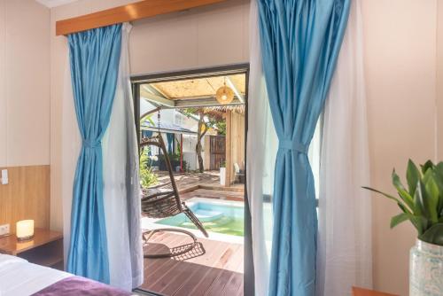 CatagnanSiargao Seasky Resort的一间带蓝色窗帘的卧室和一个游泳池