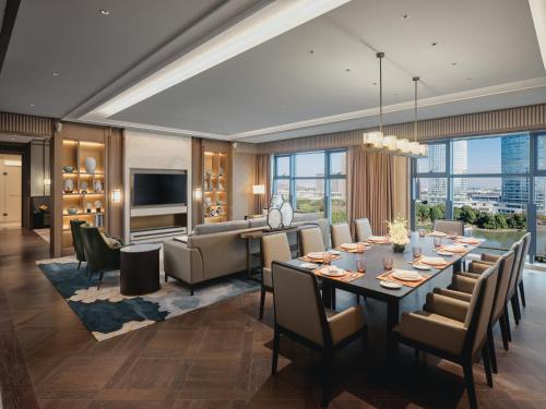 昆山HUALUXE Kunshan Huaqiao, an IHG Hotel - F1 Racing Preferred Hotel的用餐室以及带长桌和椅子的客厅