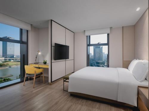 昆山Holiday Inn & Suites Kunshan Huaqiao, an IHG Hotel - F1 Racing Preferred Hotel的酒店客房设有一张床、一张书桌和一台电视机。