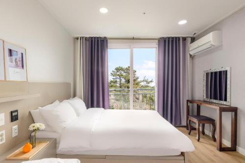 西归浦市Cordelia Hotel的一间设有大床和窗户的酒店客房