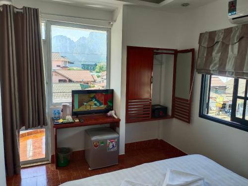 万荣Vang Vieng Trendy Hotel的一间卧室配有一张床、一台电视和一个窗口