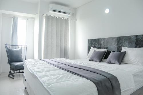 加拉旺Kia Servised Apartmen at Grand Sentraland Karawang的白色卧室配有一张大床和椅子
