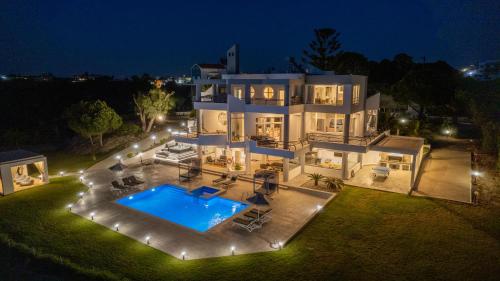 罗德镇Monte Smith Luxury Villa的一座白色的大房子,晚上设有游泳池