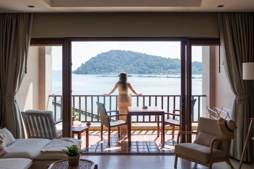 象岛Tina Holiday Homes的站在一个眺望海洋的阳台上的女人