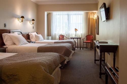 康塞普西翁HOTEL EL DORADO的酒店客房设有三张床和一张桌子