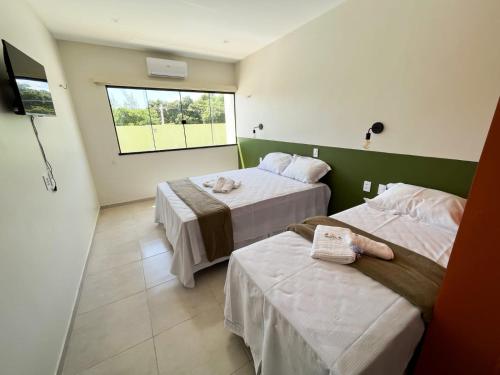巴纳伊巴Pousada Primavera的酒店客房设有两张床和窗户。
