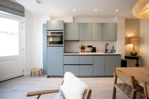 斯海弗宁恩Four Star Apartments - Badhuisstraat 6的厨房配有白色橱柜和蓝色冰箱。