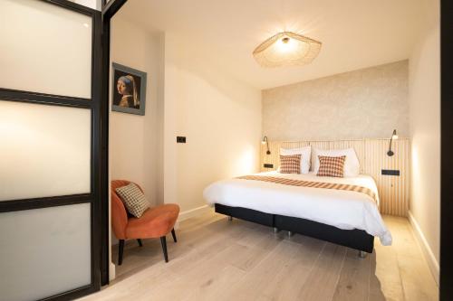 斯海弗宁恩Four Star Apartments - Badhuisstraat 6的一间卧室配有一张大床和一把椅子