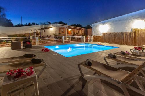 Sant RafaelVillaBlanca的后院的游泳池,晚上带两把躺椅