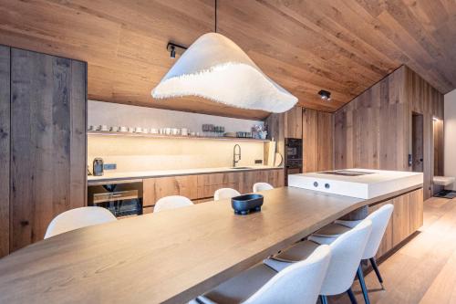 恩斯塔尔豪斯Villa Liesl by ALPS RESORTS的厨房配有大型木桌和白色椅子