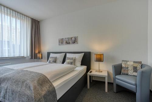 多特蒙德Hotel Carlton的一间卧室配有一张大床和一张蓝色椅子