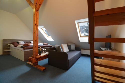 StachyHotel Churáňov的一间卧室配有高架床、一张沙发和一张床