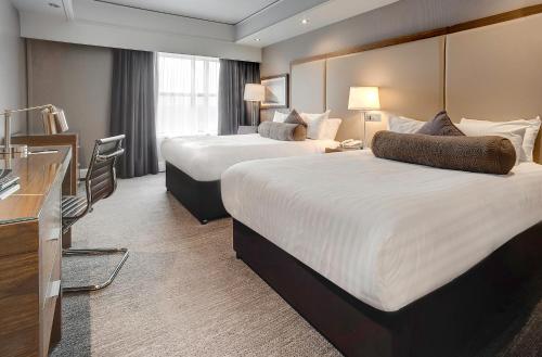 克劳利Sandman Signature London Gatwick Hotel的酒店客房配有两张床和一张书桌