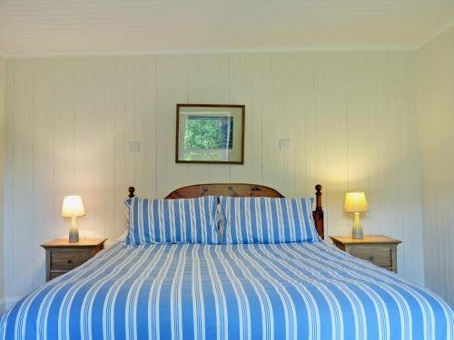 Sallachy阿什乡村别墅的一间卧室配有一张蓝色和白色条纹的床