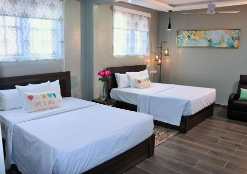 特马Lady M guest House的一间卧室配有两张带白色床单的床
