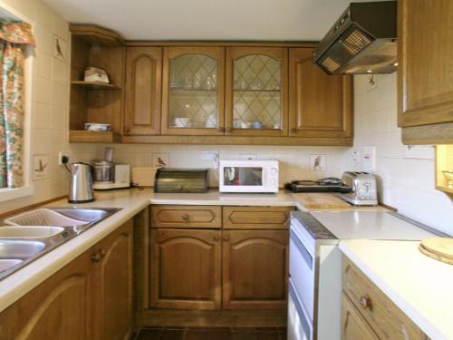 Aberarder韦斯特克鲁奇科塔乡村别墅的厨房配有木制橱柜和白色微波炉