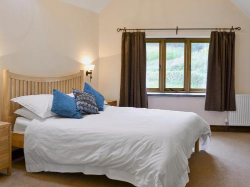 Colyton斯托汉姆乡村别墅的卧室配有带蓝色枕头的大型白色床