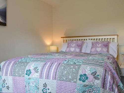瓦斯代尔下城The Retreat的一间卧室配有一张带粉红色和紫色棉被的床