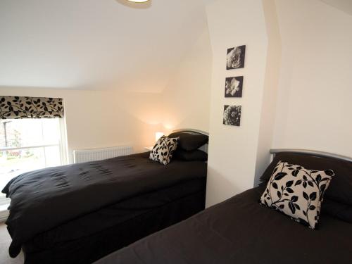 查珀尔圣伦纳兹Somer Leyton Cottage的一间卧室设有两张床和窗户。