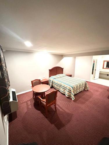 BellTropic West Motel的酒店客房带一张床、一张桌子和椅子