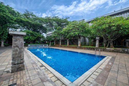 雅加达Oakwood Hotel & Apartments Taman Mini Jakarta的一座大游泳池,位于一个树木繁茂的庭院内