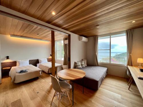 下田白滨花园别墅酒店的客房设有两张床、一张桌子和一张书桌。
