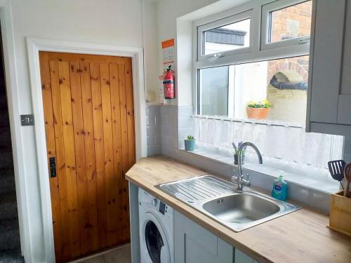 奥尔弗里顿安伯利小屋乡村别墅的厨房配有水槽和洗衣机