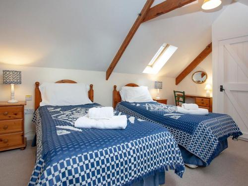 Crackington Haven圆屋乡村别墅的一间卧室配有两张带蓝白色床单的床