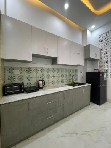 Ấp Lợi ÐủHO GIA AN Home - King Room的厨房配有白色橱柜和黑色冰箱。