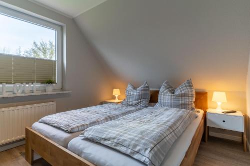 OlsdorfStrandperle的卧室配有带枕头的床铺和窗户。
