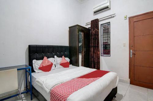 杜迈OYO 92111 Dinda Homestay Syariah的一间卧室配有一张带红色枕头的床