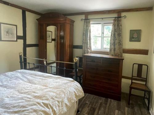 Longhope小屋乡村别墅的一间卧室配有一张床、一个梳妆台和一扇窗户。